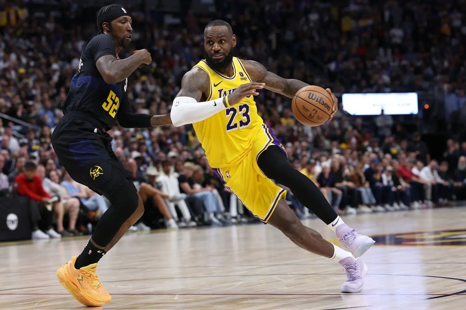 LeBron James in a yellow Lakers jersey dribbling the basketball during a game.
