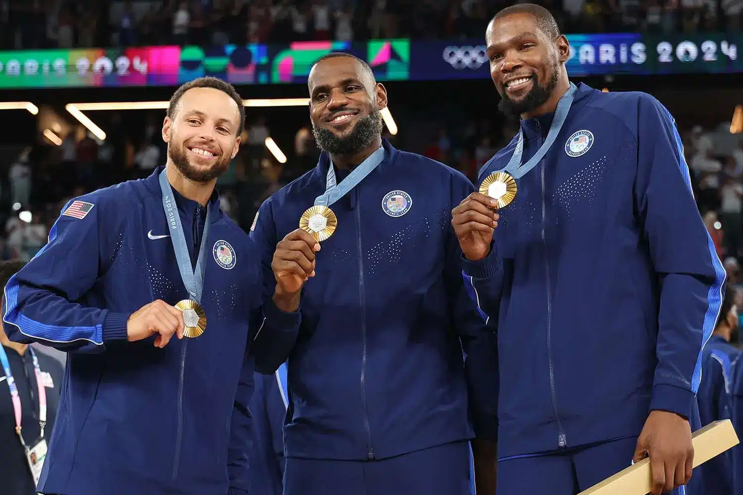 Stephen Curry, LeBron James, and Kevin Durant posing with gold medals at the Paris 2024 Olympics
