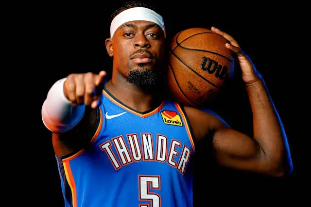 Lu Dort in an Oklahoma City Thunder jersey holding a basketball.