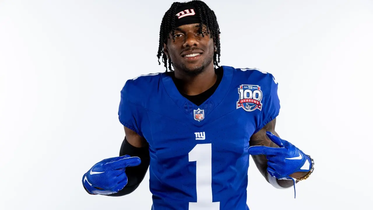 Football player in blue New York Giants jersey pointing at himself.