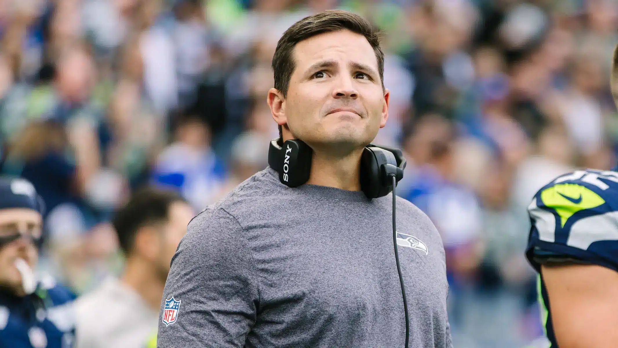 Mike Macdonald on the sidelines during a Seahawks game, wearing team gear.