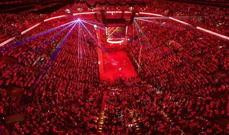 A packed Moda Center in Portland during an event with red lighting and laser beams.