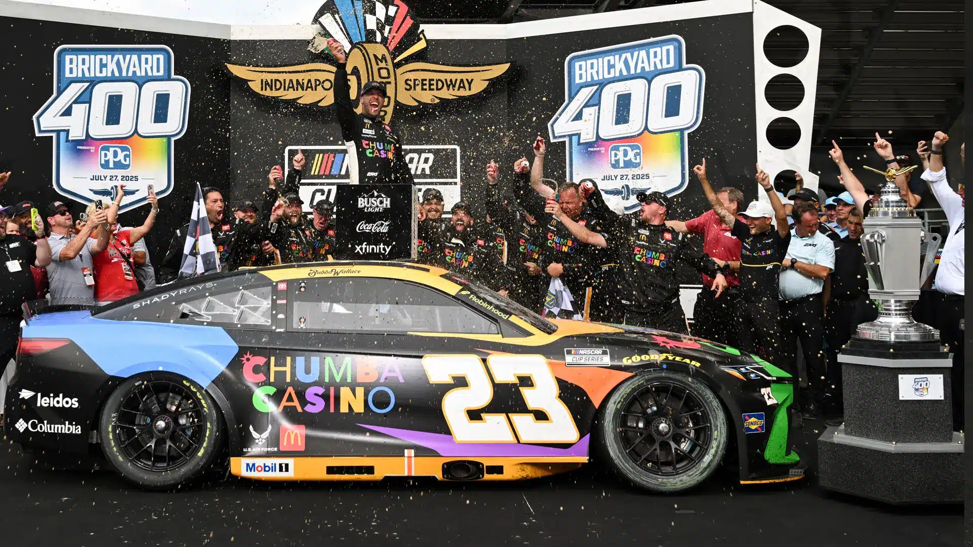 Race winner celebrating with crew beside car at Brickyard 400 victory lane.