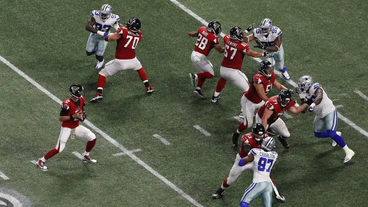 Atlanta Falcons offensive linemen blocking defenders during a game play.