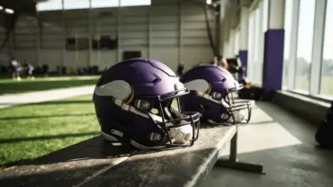 Two Minnesota Vikings helmets on practice facility bench symbolizing quarterback competition