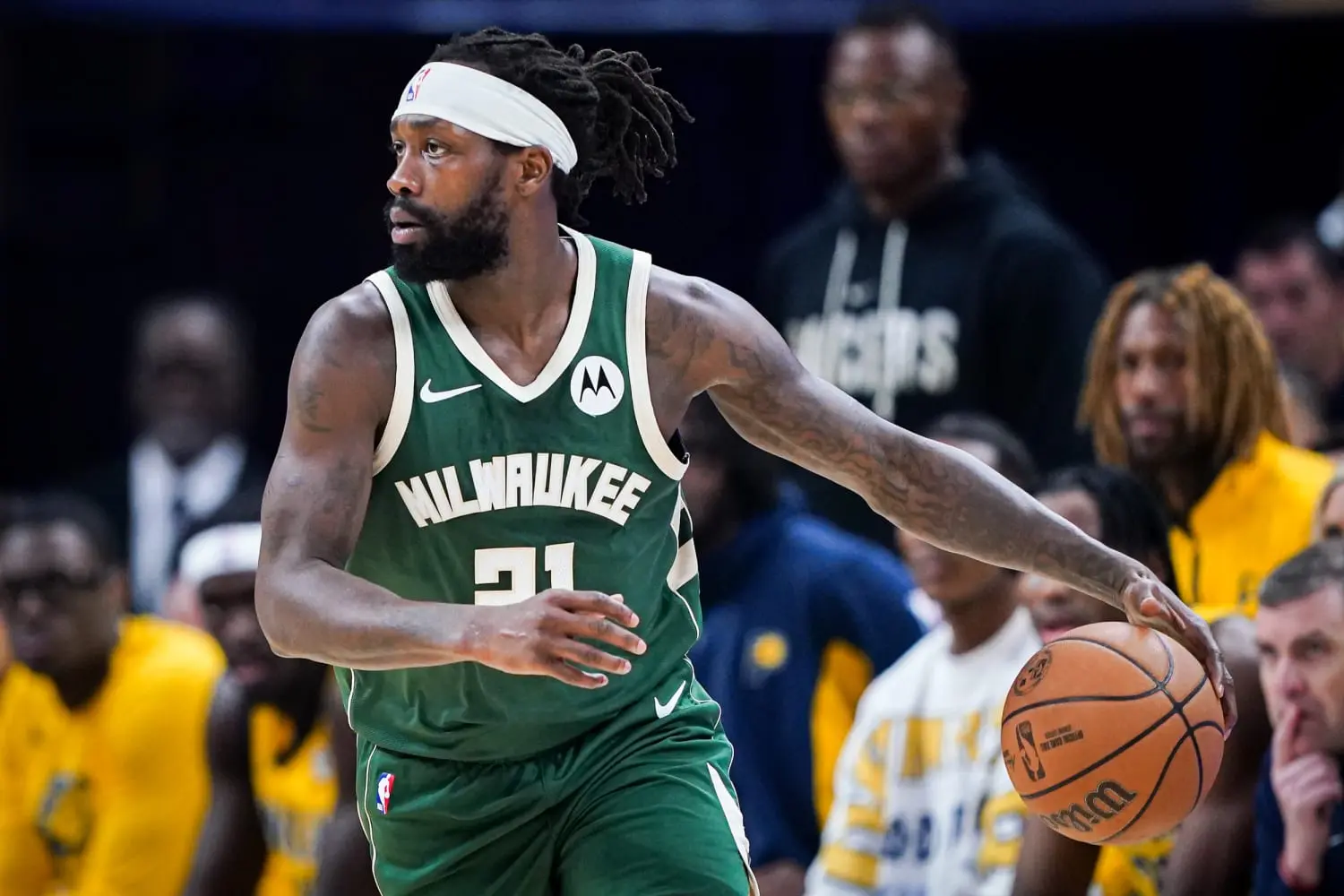 Basketball player wearing a Milwaukee jersey dribbling a ball during a game.