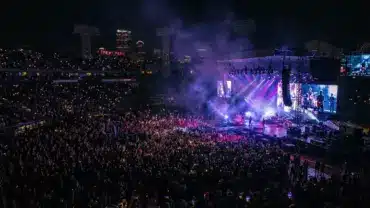 Fenway Park concert stage at night with crowd and dramatic lighting