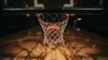 Basketball dropping through hoop net from below, dramatic sports photography lighting