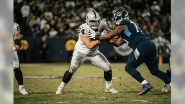 Raiders center in pass-protection stance blocking defensive lineman at line of scrimmage
