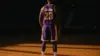 LeBron James in Lakers jersey standing contemplatively on empty basketball court with dramatic lighting