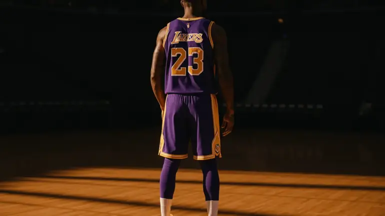 LeBron James in Lakers jersey standing contemplatively on empty basketball court with dramatic lighting