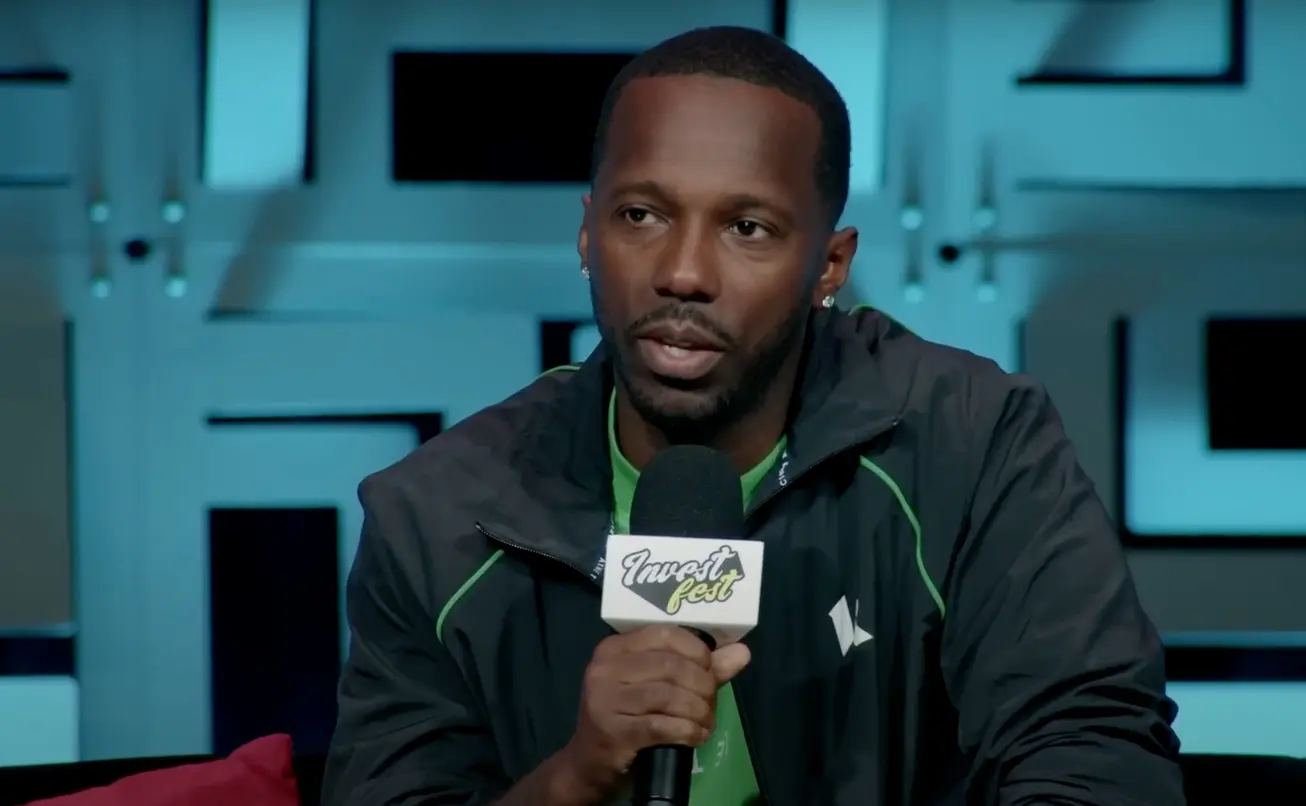 Rich Paul speaking at an event, wearing a black and green jacket.