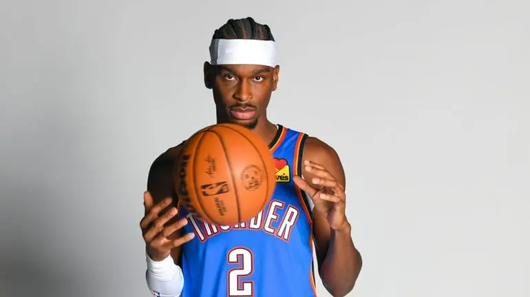 Shai Gilgeous-Alexander posing with a basketball in his Thunder jersey.