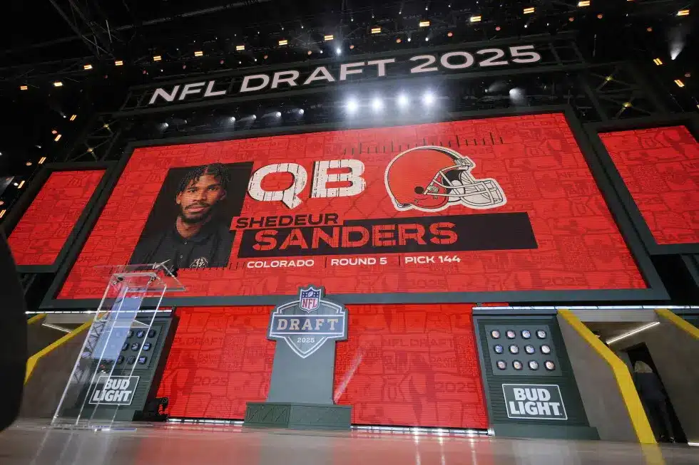 Shedeur Sanders displayed on a large screen at the NFL Draft 2025.