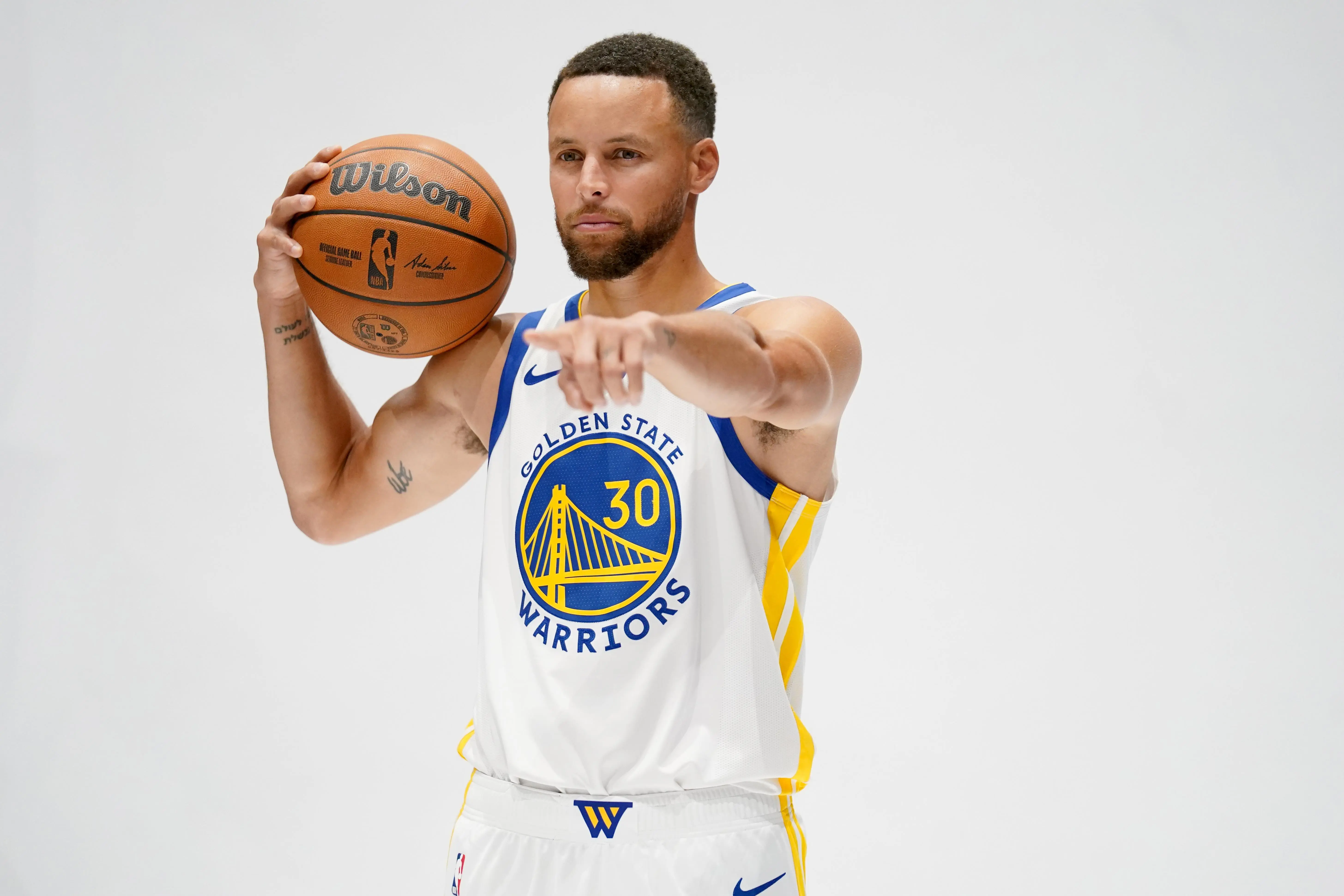Stephen Curry in a Golden State Warriors jersey holding a basketball.