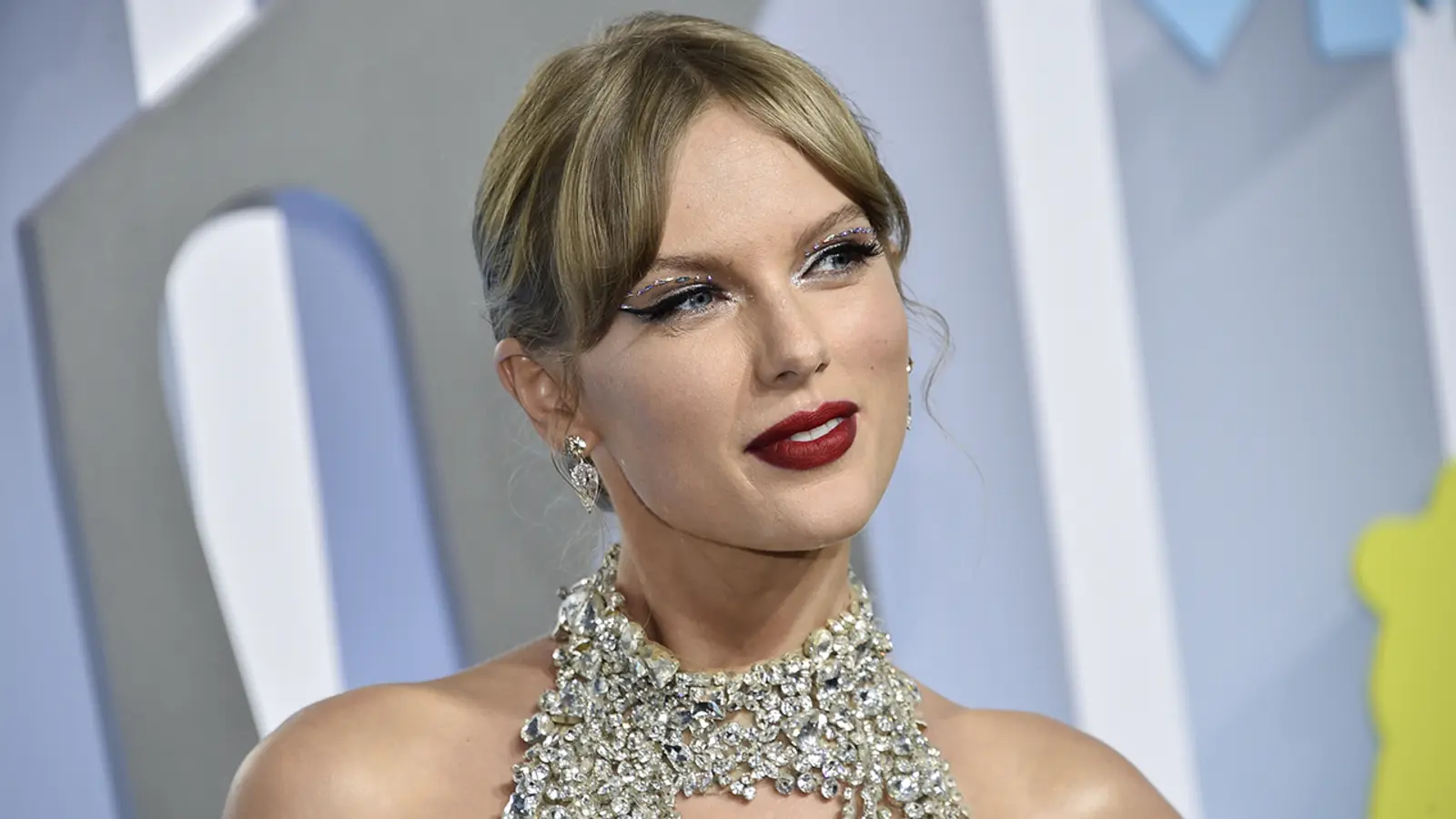 Taylor Swift wearing a sparkling dress at an event with dramatic makeup.