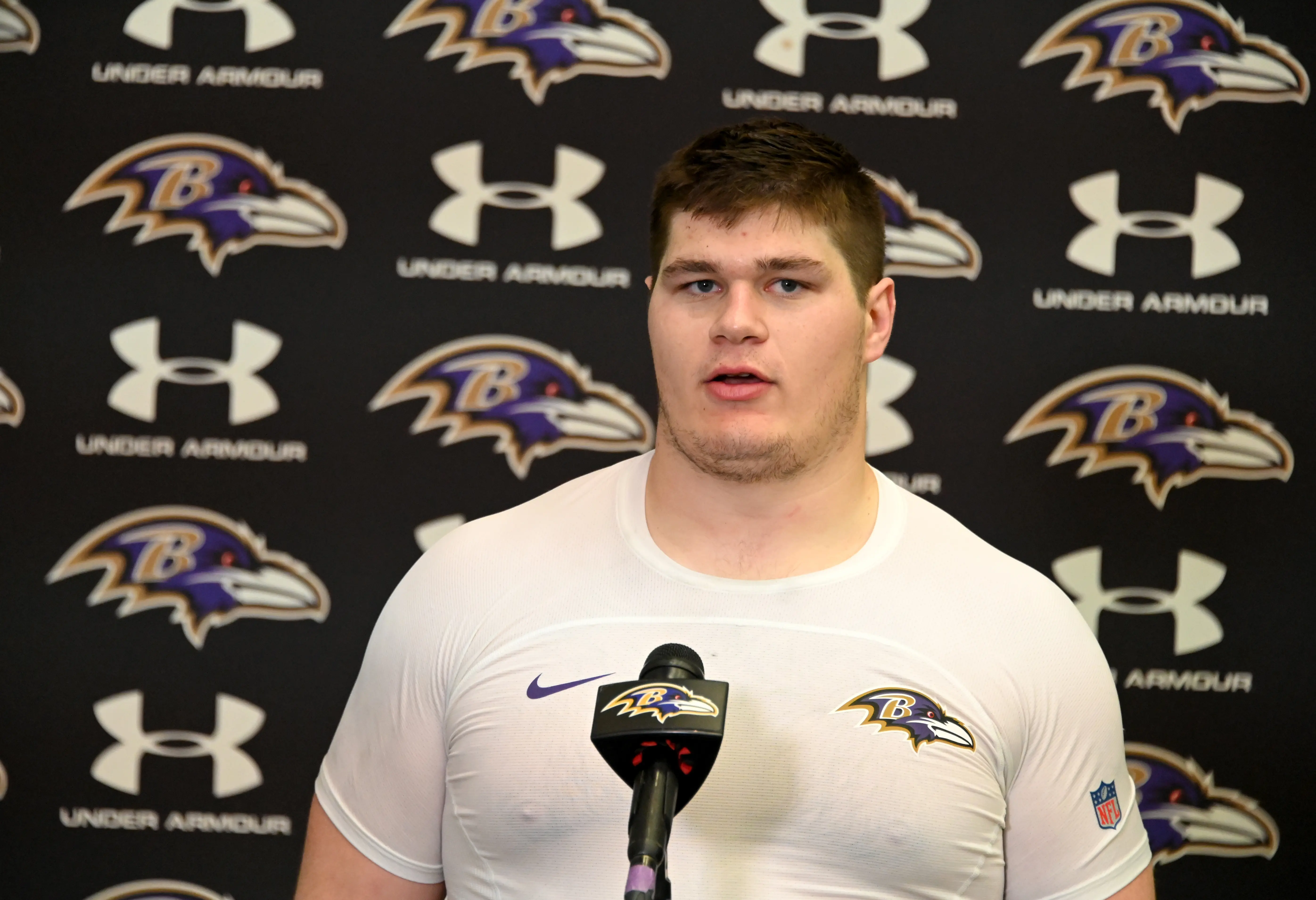 Tyler Linderbaum speaking at a press conference in Ravens gear.