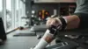 Football player's knee in medical wrap on rehab bench with Chiefs colors in background