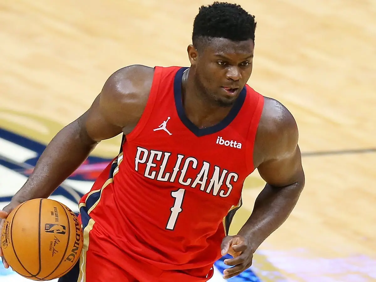 Zion Williamson dribbles a basketball wearing a Pelicans jersey during a game.