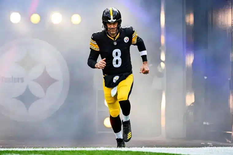 A football player wearing a Pittsburgh Steelers jersey with number 8 running onto the field through smoke.