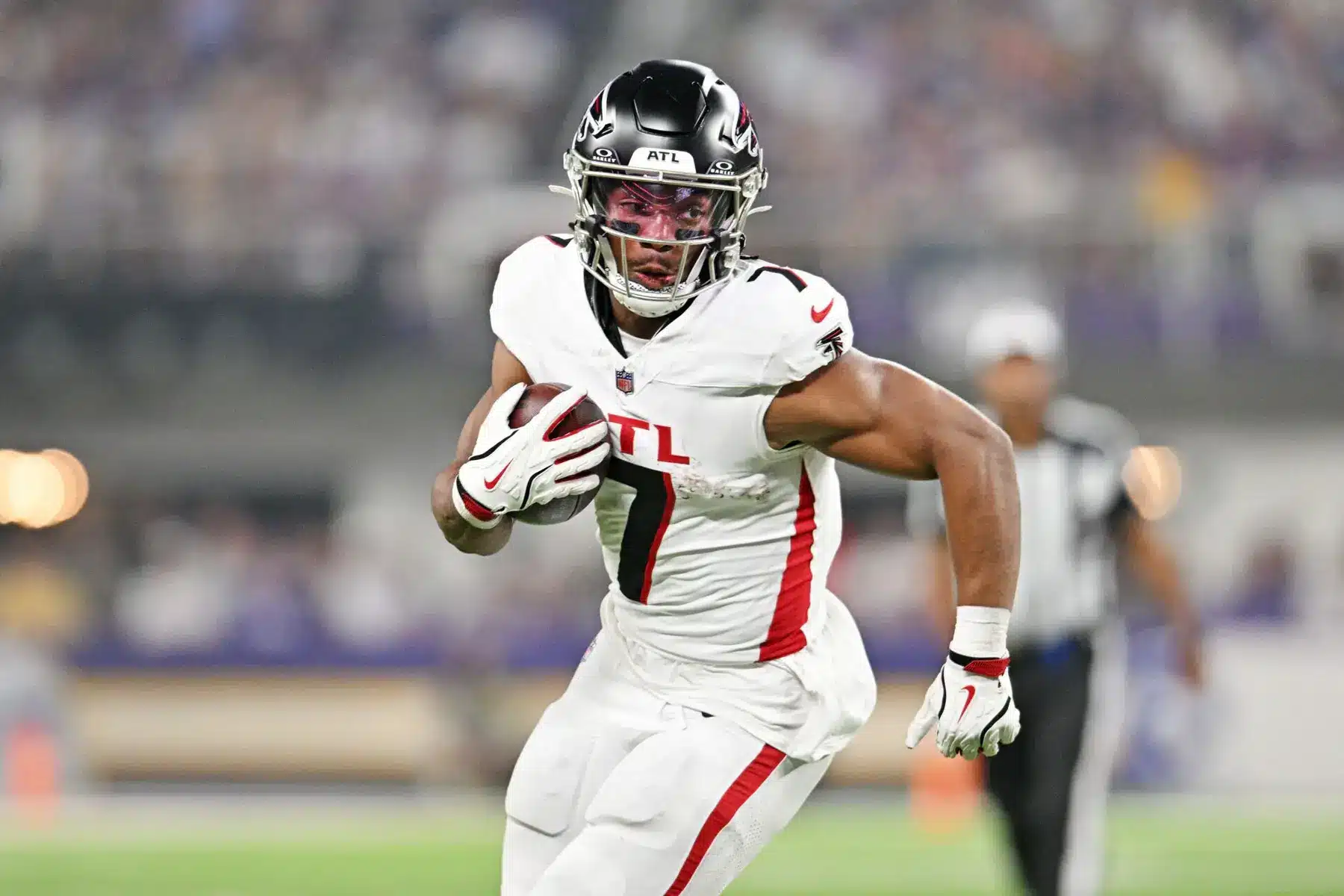 Atlanta Falcons running back Bijan Robinson carrying a football during a game in a white uniform.