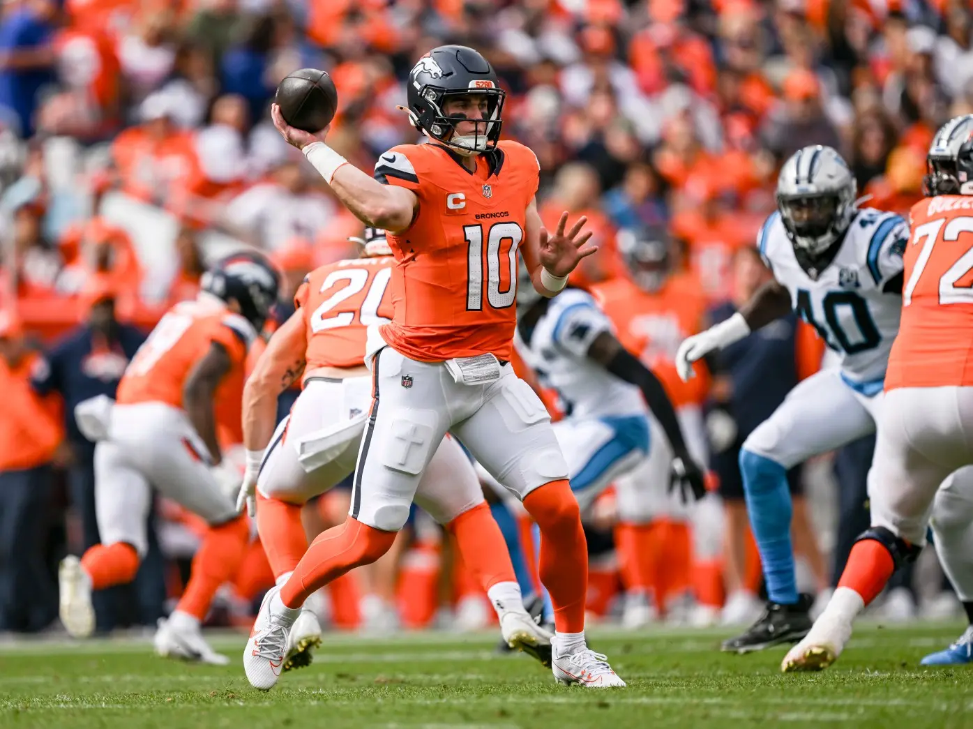 Denver Broncos quarterback Bo Nix in orange jersey throwing a football during a game