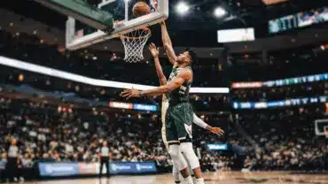 Basketball player blocking shot at rim with extended arms during professional game