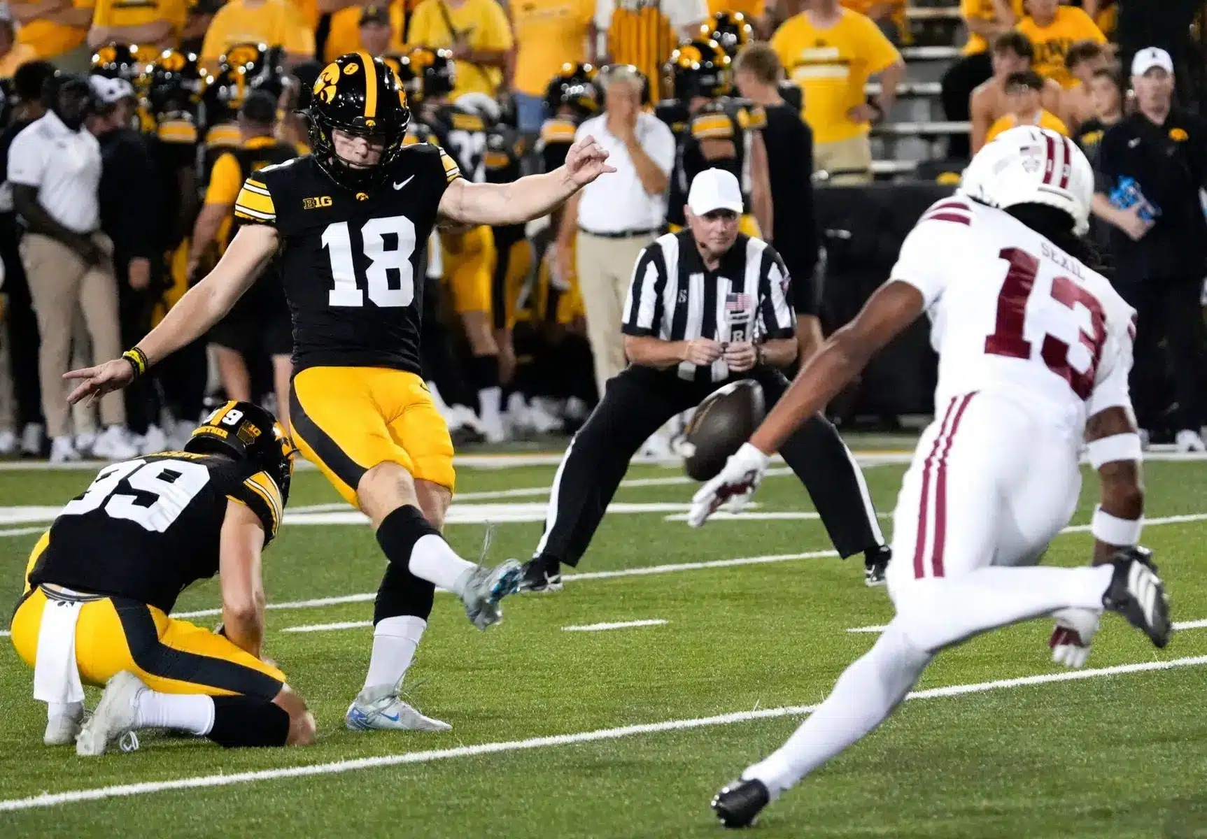 Iowa Hawkeyes kicker Drew Stevens wearing number 18 kicking a football during a game.