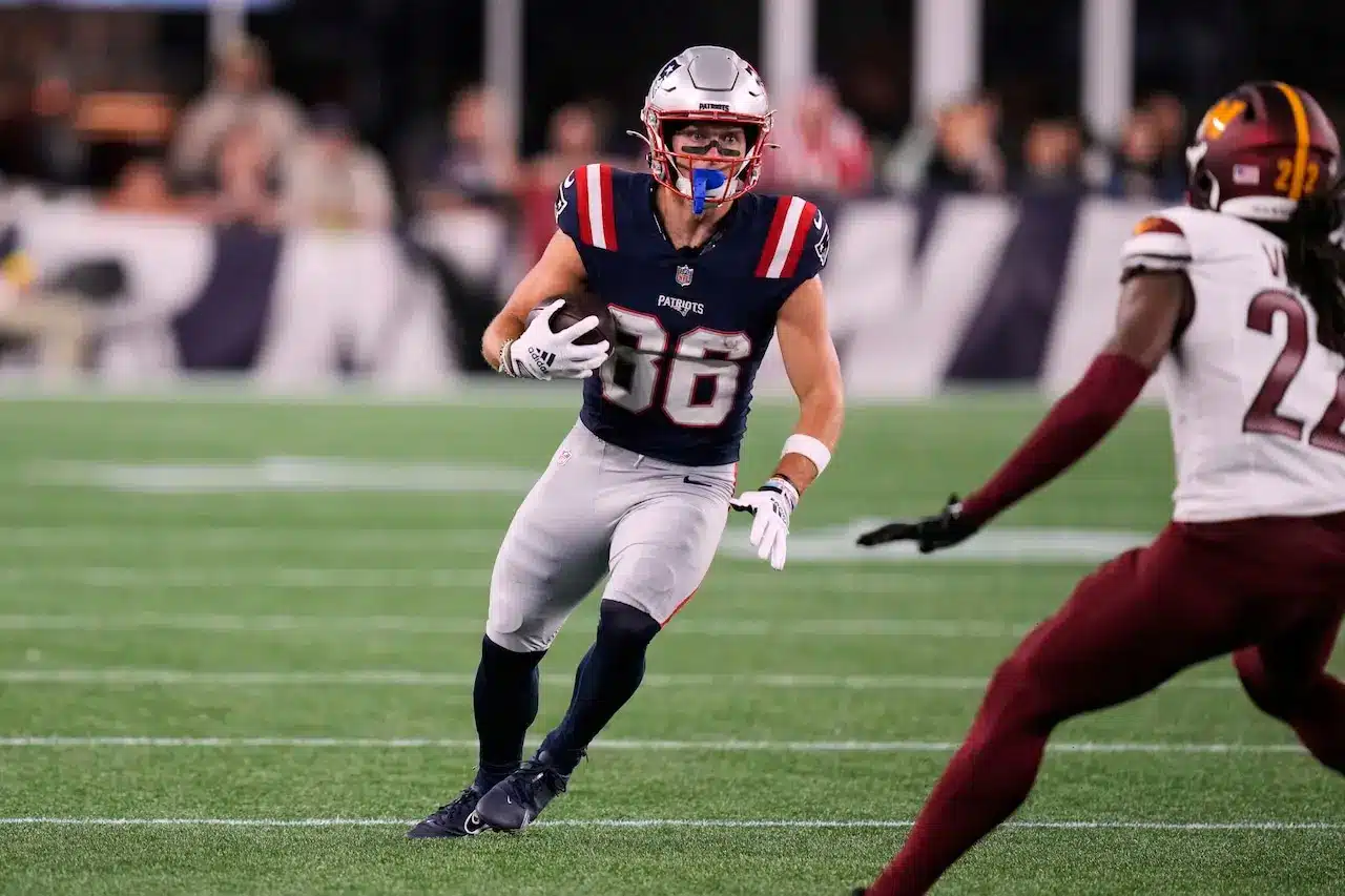 New England Patriots player Efton Chism wearing jersey number 66 and carrying a football during a game.