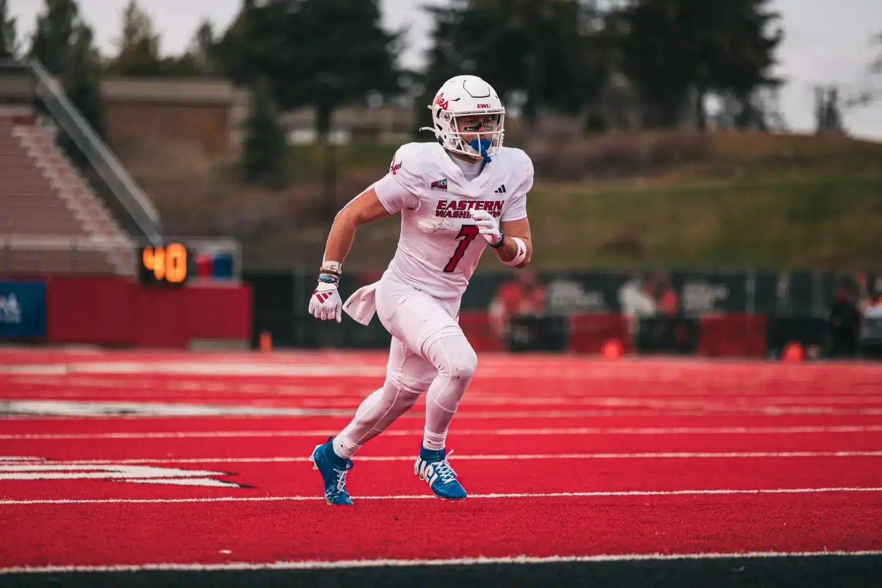 Efton Chism III wearing an Eastern Washington University football uniform running on a red turf field.