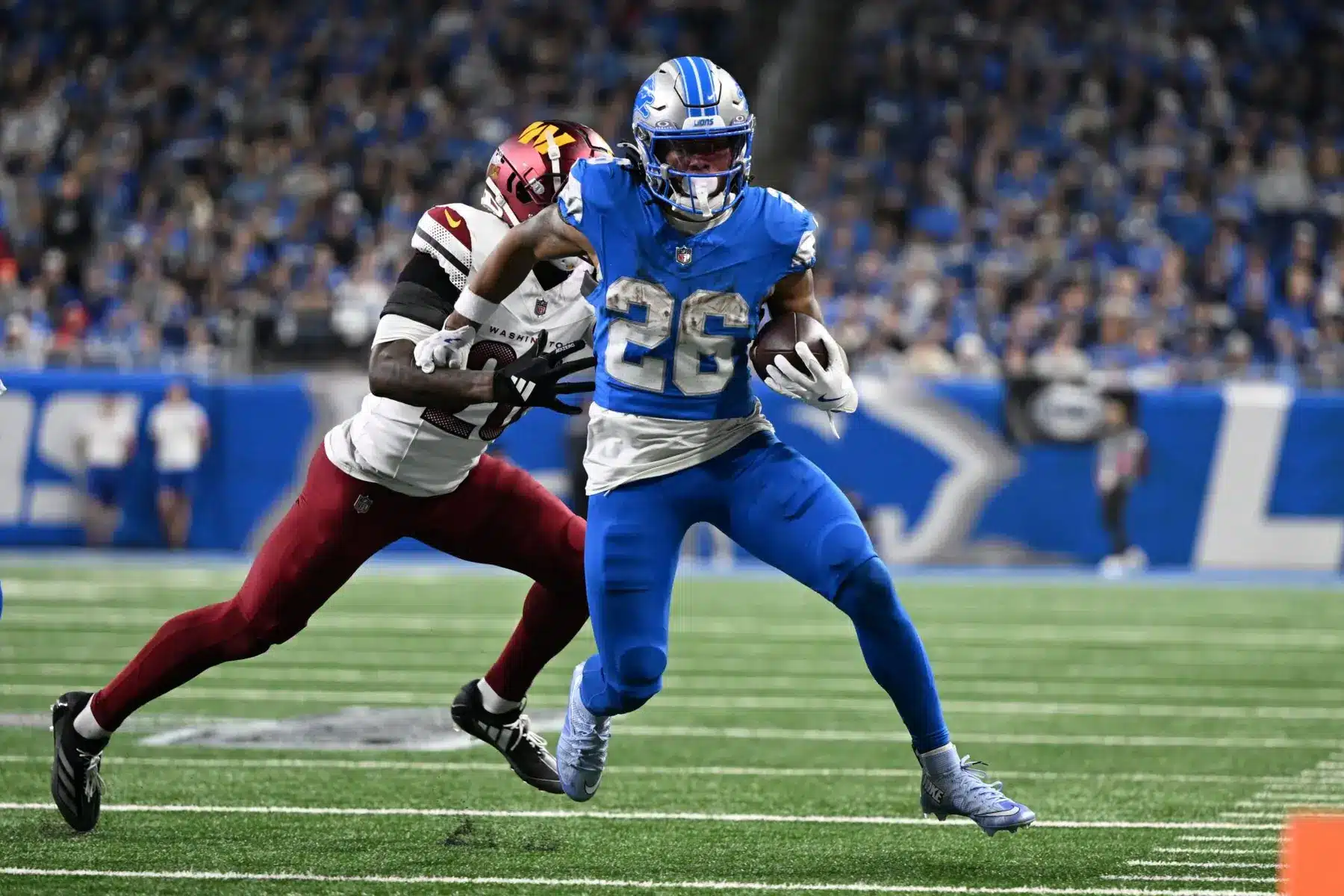 Detroit Lions running back Jahmyr Gibbs wearing jersey number 26 carrying a football during a game