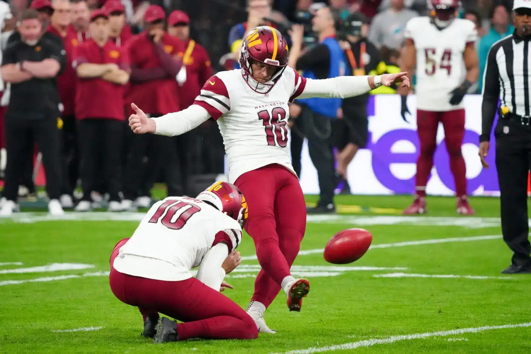 Washington Commanders kicker number 18 kicking a football during a game