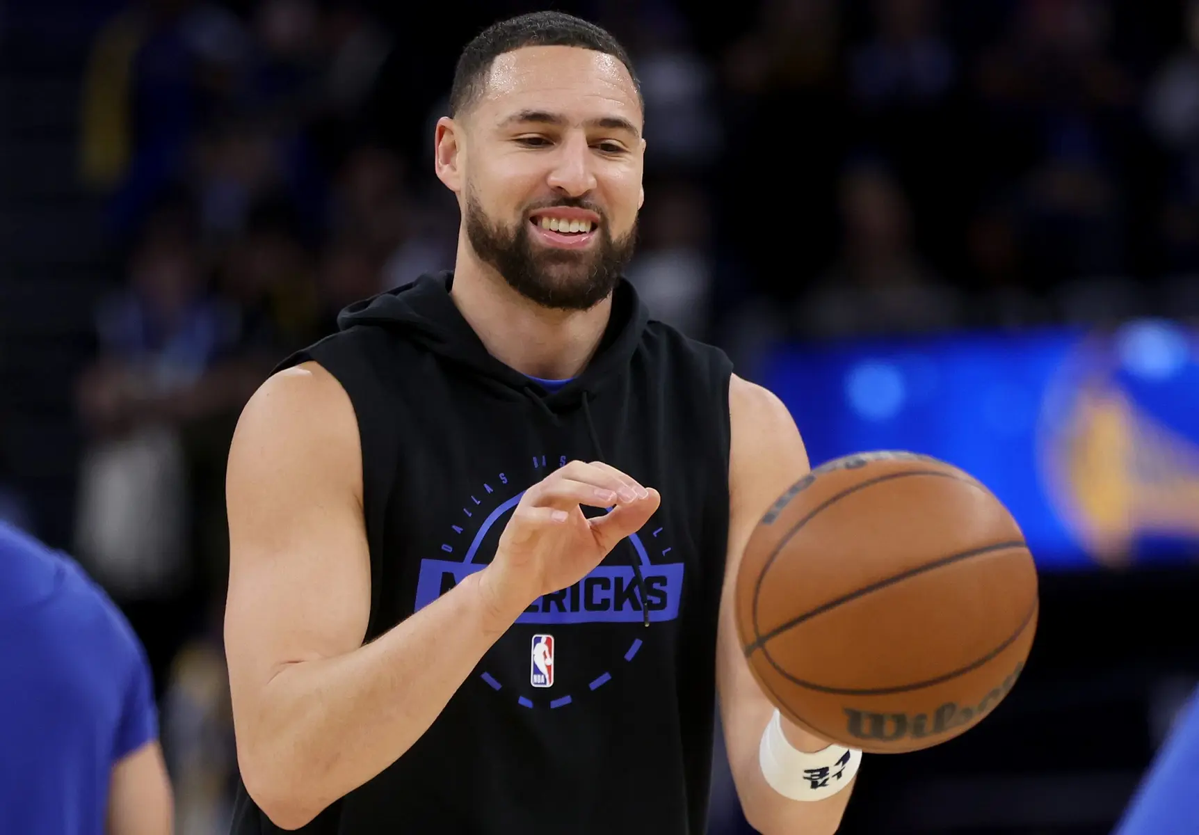 Klay Thompson wearing a black Dallas Mavericks practice hoodie and holding a basketball