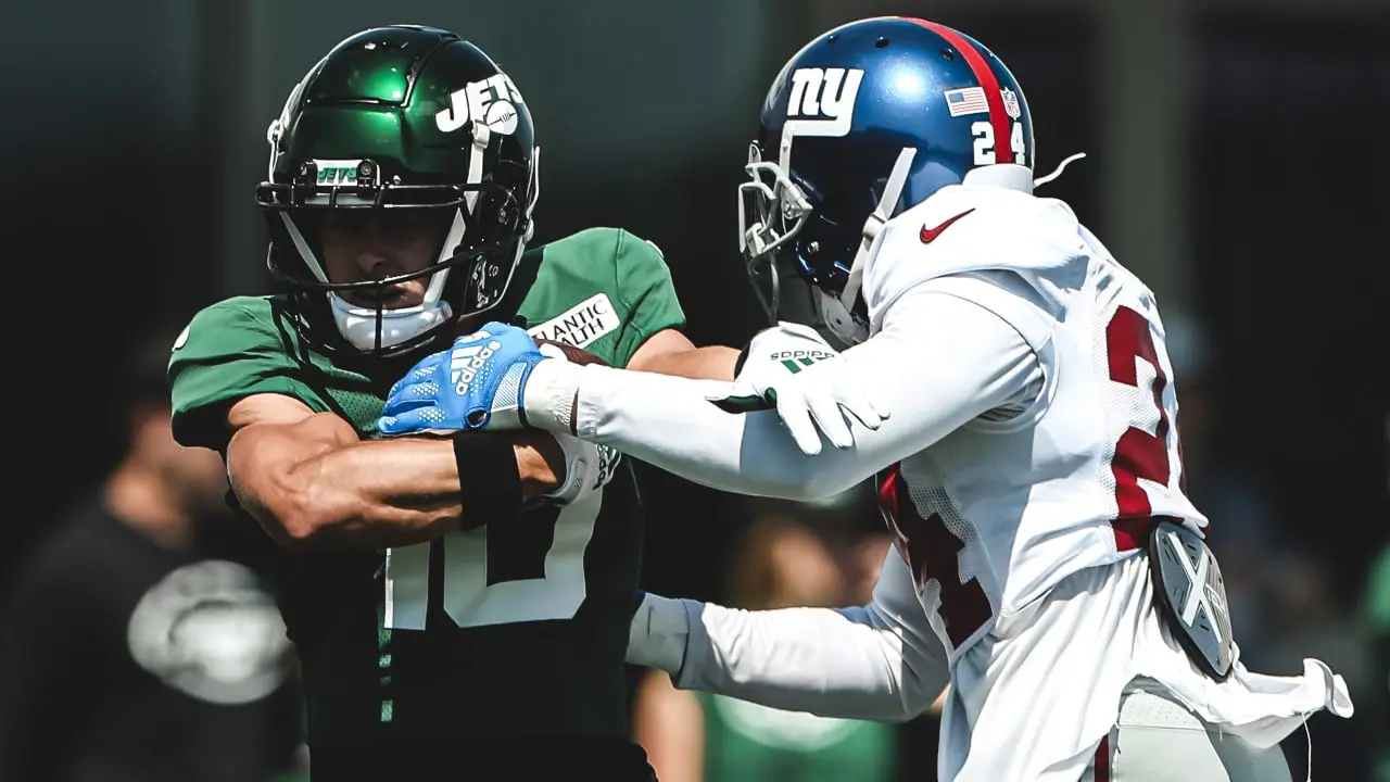 A New York Jets player in a green jersey and a New York Giants player in a white jersey competing during a game.