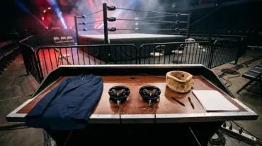 Empty wrestling commentary desk and ring after a dramatic live event, symbolizing Pat McAfee’s WWE exit