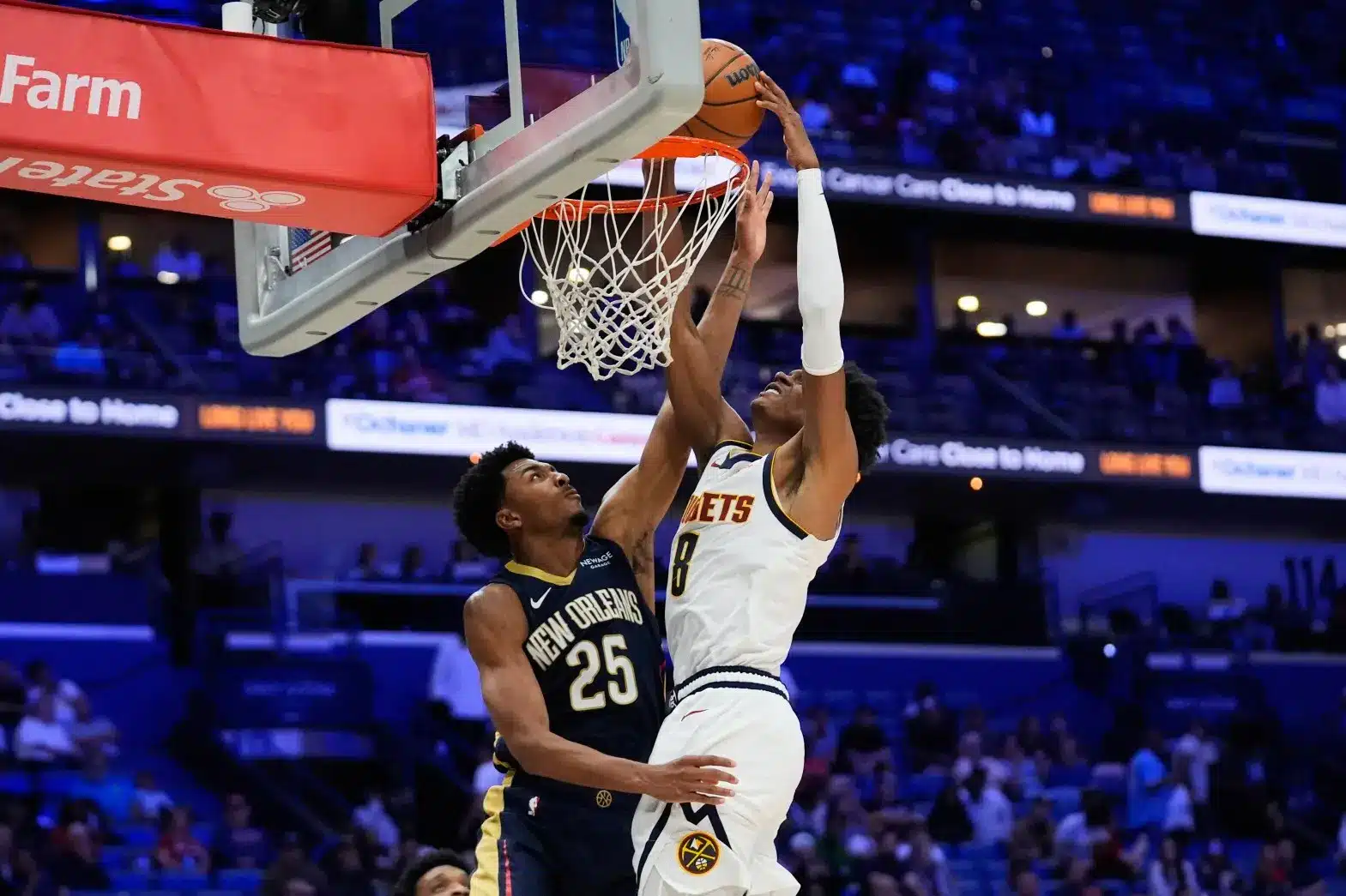 Peyton Watson of the Denver Nuggets jumping for a layup against a New Orleans Pelicans player.