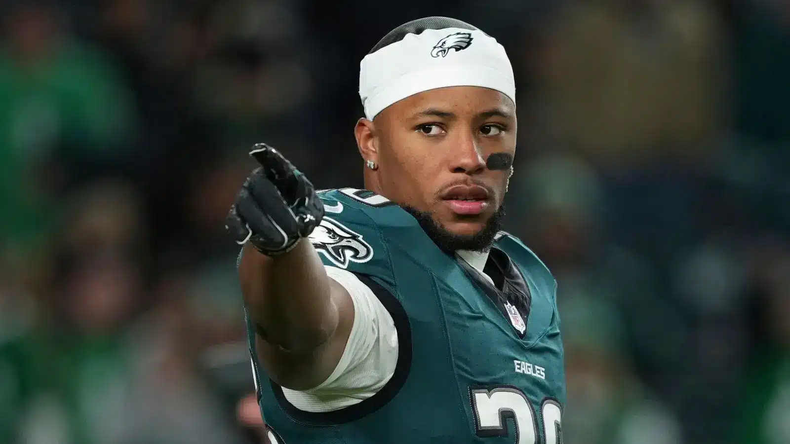 Saquon Barkley in a Philadelphia Eagles jersey and white headband pointing forward on the field