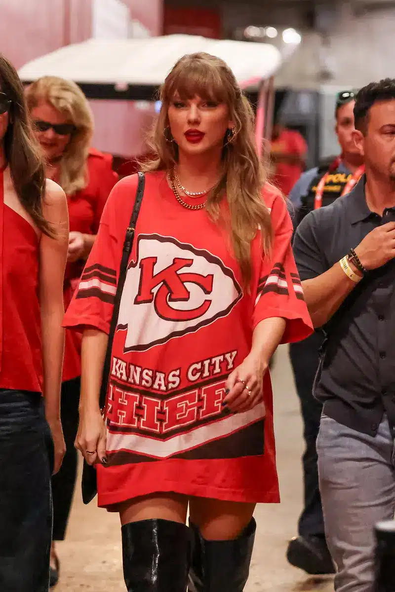 Taylor Swift wearing an oversized red Kansas City Chiefs jersey and black boots