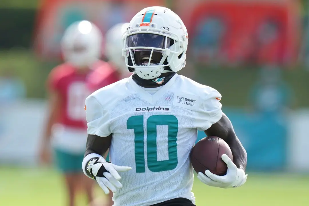 Tyreek Hill of the Miami Dolphins wearing a white jersey with number 10 and carrying a football