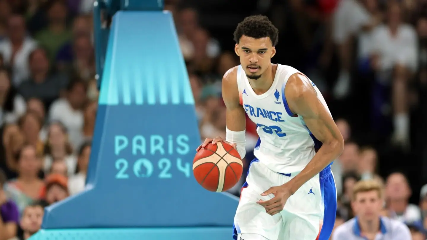 Victor Wembanyama in a white France national team jersey holding a basketball at the Paris 2024 Olympics