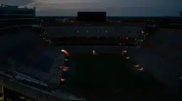 Darkened college football stadium during a power outage with the field faintly lit by emergency lights
